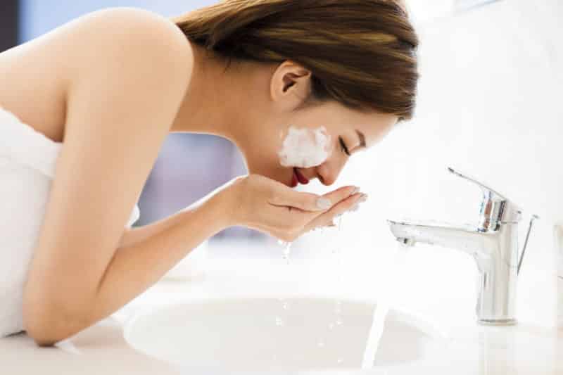 woman washing face with clean water